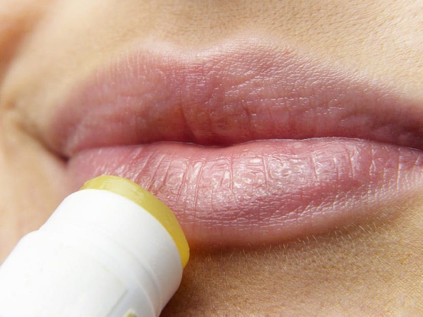mujer hidratandose los labios secos