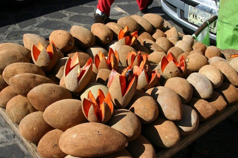 Mameys colorados enteros y abiertos en un puesto de fruta