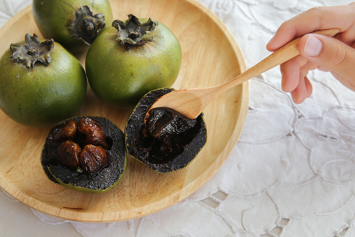 frutas del zapote negro dentro de un cuenco de madera