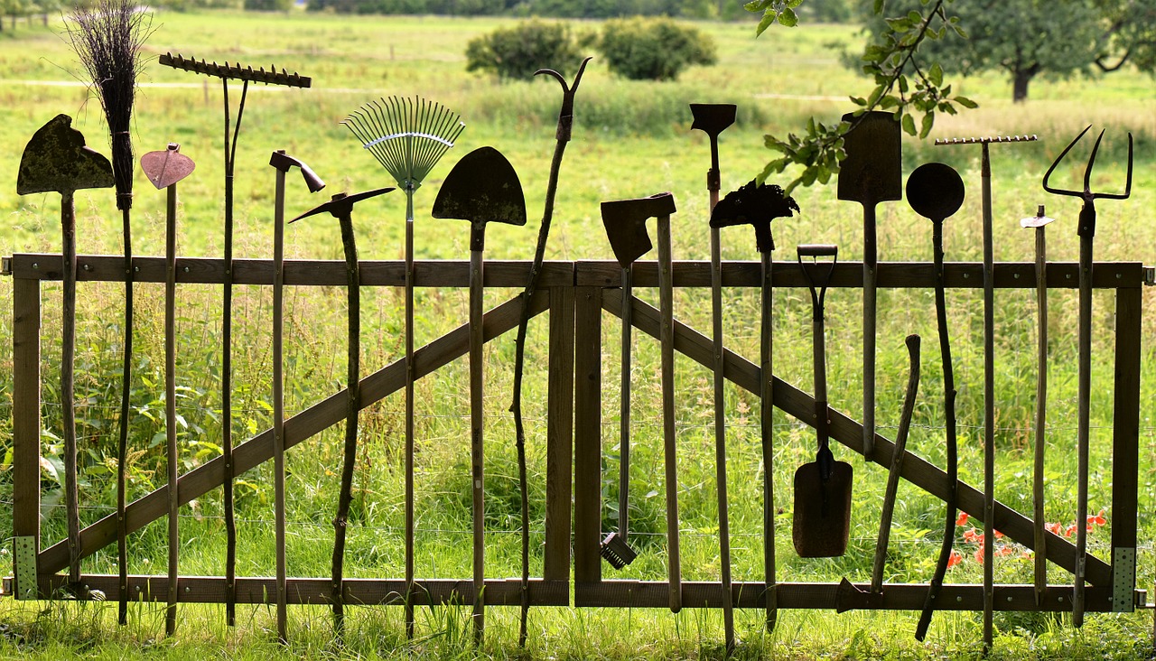Valla de madera de jardín con cancela y herramientas apoyadas