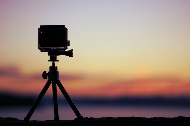 Cámara compacta sobre un trípode pequeño con el cielo al atardecer